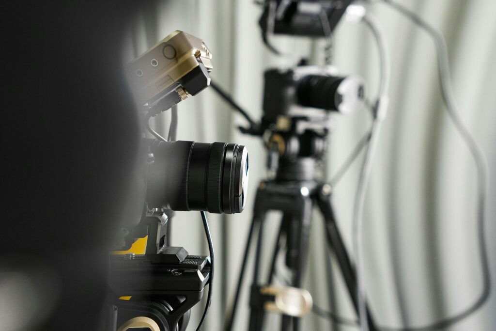 Close-up of professional video cameras on tripods in a studio setting.
